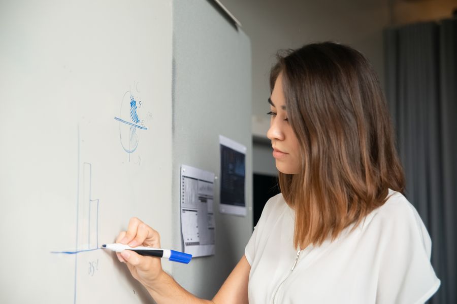 Business woman drawing graphs on a whiteboard during a meeting.