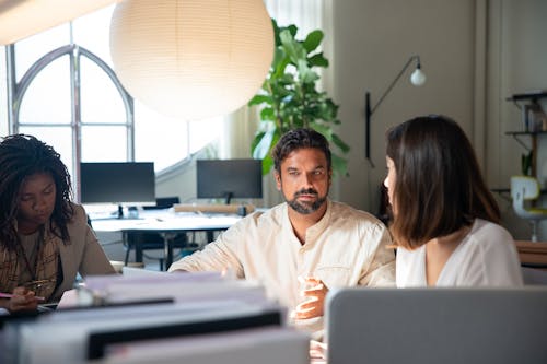 Photo of a Man Talking to His Coworker in the Office