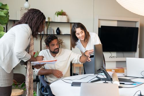 Free Diverse team engaged in collaborative discussion around computer in modern office. Stock Photo