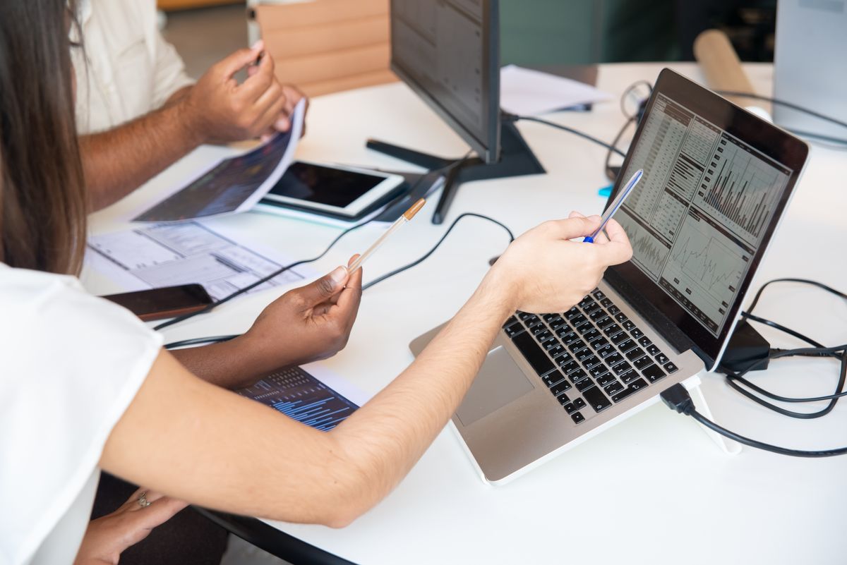 Business professionals discussing data and charts on a laptop