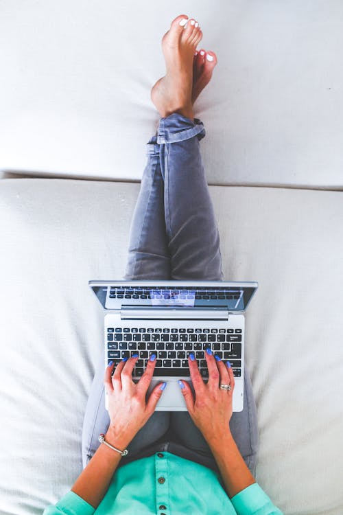 Free Woman lying and typing on laptop Stock Photo