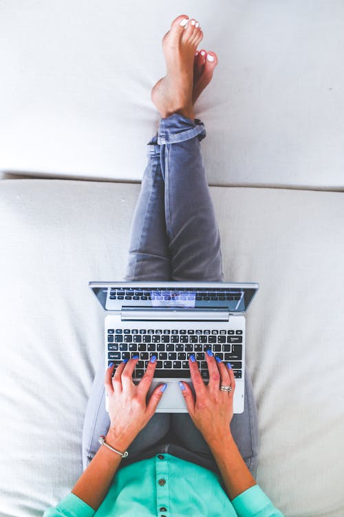 Woman lying and typing on laptop