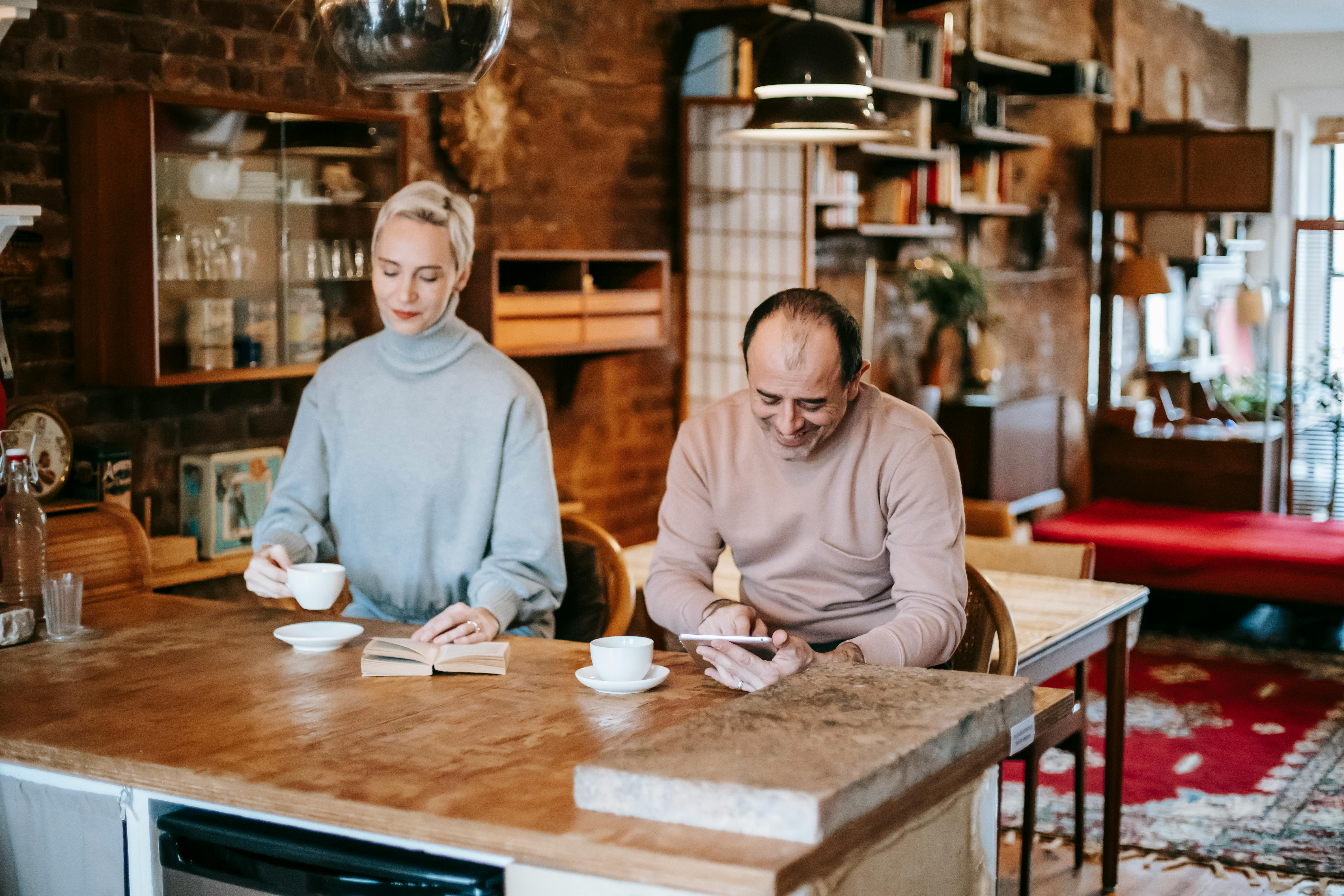 woman reading book sitting near man scrolling tablet