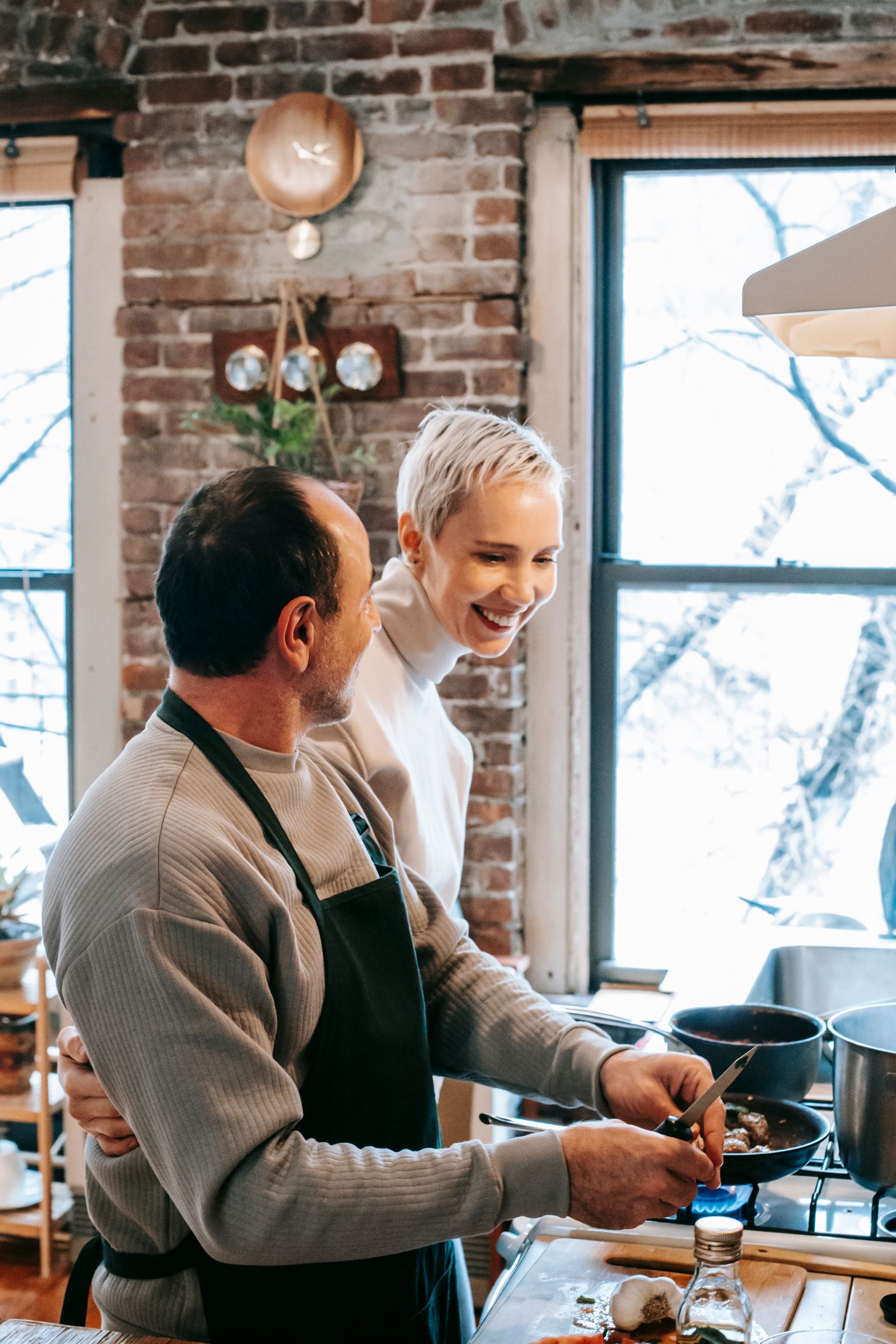A couple sharing a warm, playful moment while cooking together at home