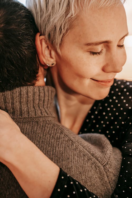 Crop romantic wife gently smiling with closed eyes while embracing husband during romantic moment