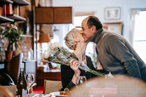 Free Woman Holding Bouquet of Flowers Kissing a Man Stock Photo