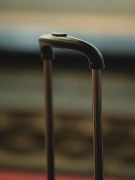 Modern metal replaceable telescopic pull out travel luggage handle placed on street in city on blurred background on evening time
