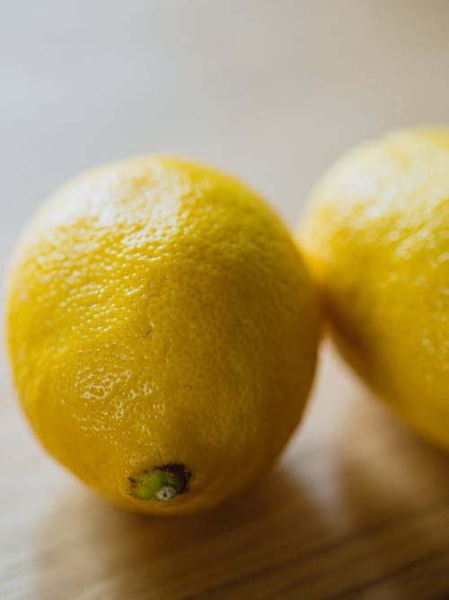 From above of ripe whole sour citrus lemons placed on wooden table in light room on blurred background in kitchen