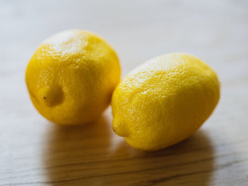 Ripe sour whole lemons placed on wooden surface in light room in kitchen with sunlight at home during harvest season
