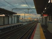 Railroad station with metal rails and glowing signboards on street in city with cables and buildings in distance on evening time