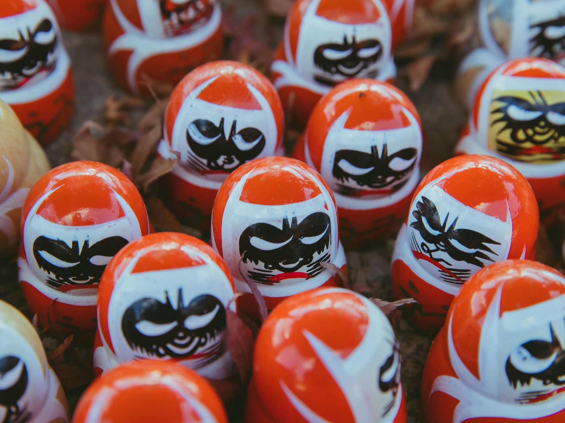 From above set of red traditional Japanese daruma dolls with black painted faces symbolizing good luck placed together on street