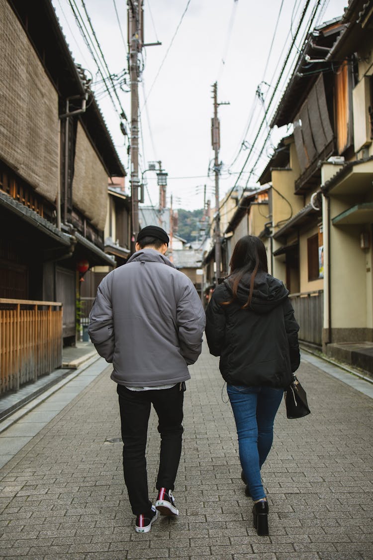 Couple Walking On Street With Concrete Tile And Old Houses