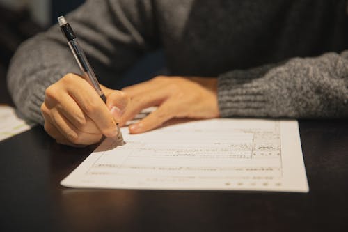 Free Man filling in form on parer at table Stock Photo