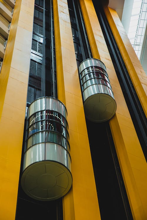 From below inside of high geometric modern multistory complex with round shaped lifts