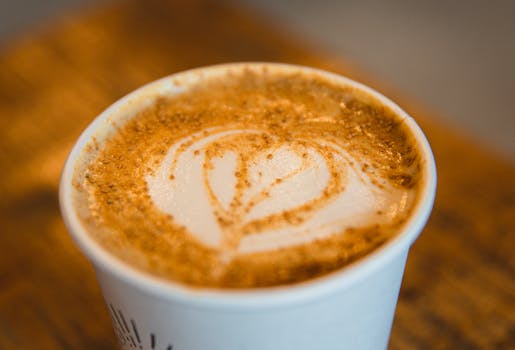 From above closeup of cup of hot aromatic cappuccino with art froth at table in coffee shop