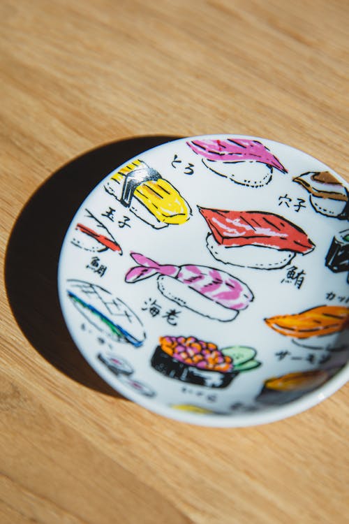 Free From above of sushi rolls painted on ceramic plate placed on wooden table Stock Photo