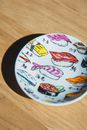 From above of sushi rolls painted on ceramic plate placed on wooden table