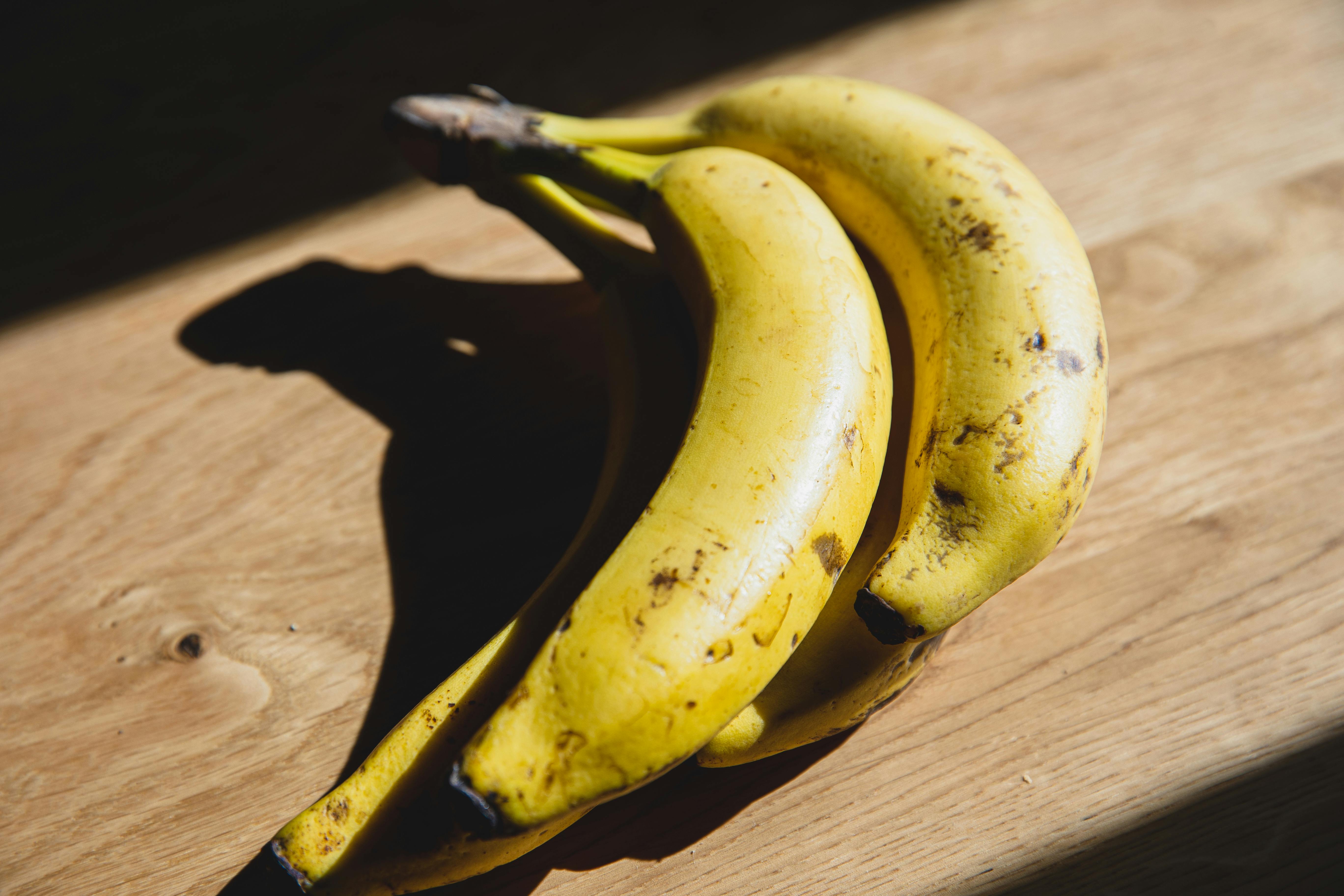 ripe bananas placed on wooden table in sunlight