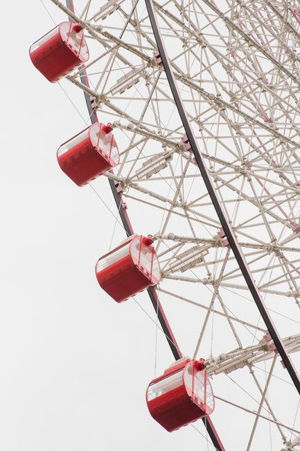 From below of Ferris wheel with metal cabins for observation territory from above