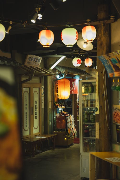 Free Illuminated Chinese lanterns illuminating street with shops and hieroglyphs on showcases at night Stock Photo