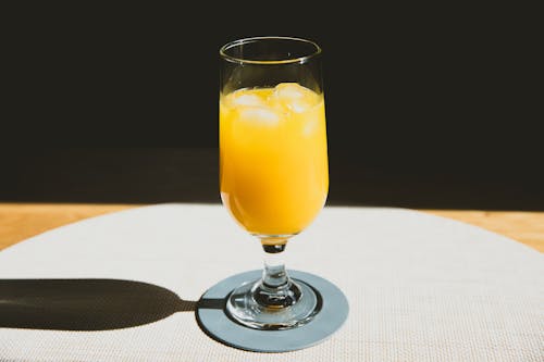 Free Crystal glass of cold refreshing orange juice with ice cubes placed on table Stock Photo