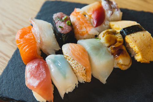 Free From above of assorted traditional Japanese nigiri sushi with raw fish and egg crepe served on black tray Stock Photo