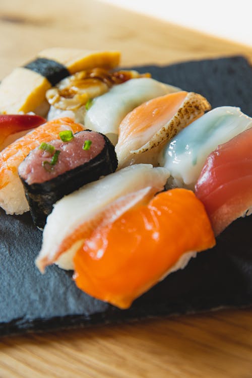 Free From above of nigiri sushi with different toppings of raw fish served on black slate plate Stock Photo