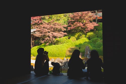 Unrecognizable people sitting on step near garden with plants