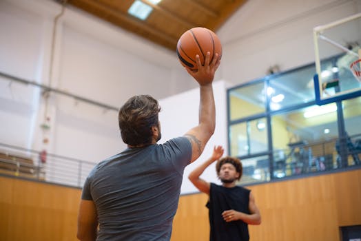 Two adult men playing an intense game of basketball indoors, capturing action and movement.