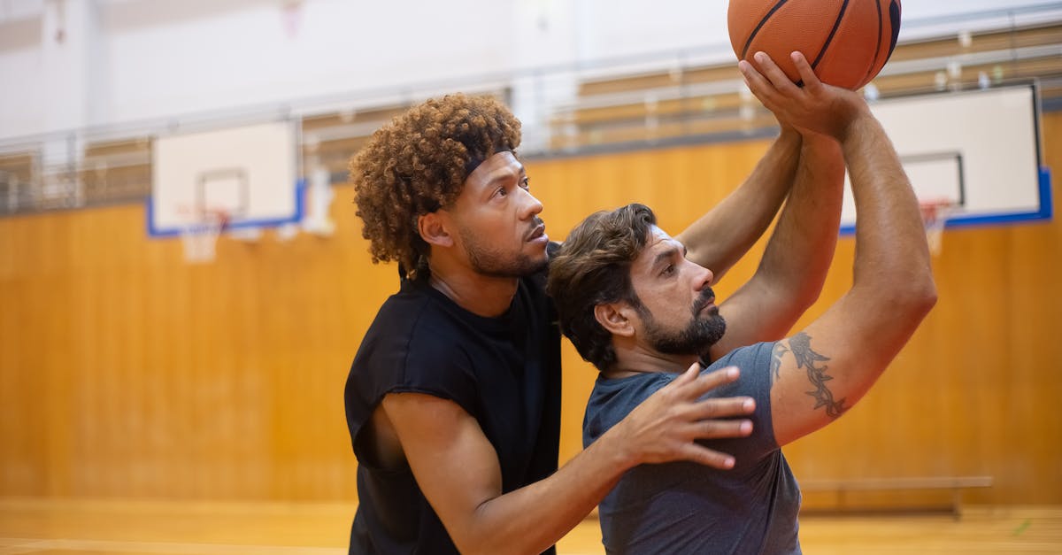 Photo of a Man with Curly Hair Guiding Another Man to Shoot a Ball