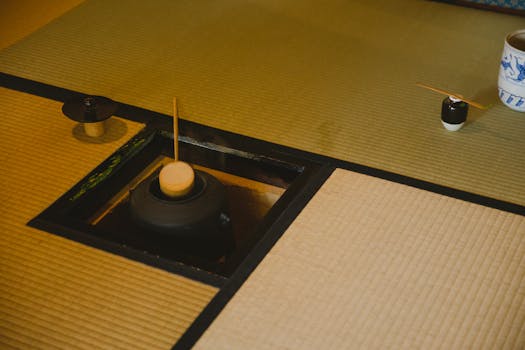 High angle of traditional Japanese tea ceremony in Urasenke style in spacious light room on floor with fire pit with kettle and water ladles near pot