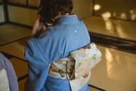 Back view of unrecognizable person wearing authentic robe sitting on tatami while drinking tea from bowl during traditional Japanese ceremony