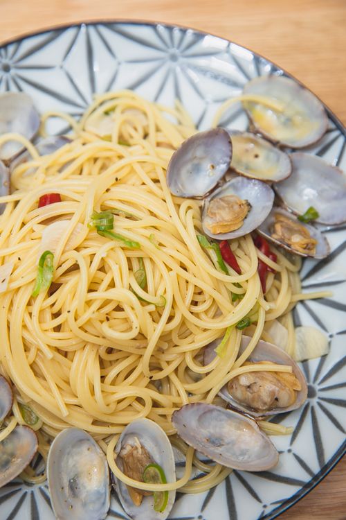 Free Top view of tasty spaghetti with mussels topped with green onion and red pepper served on ceramic round plate and placed on table Stock Photo