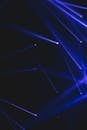 Chaotic abundance of blue beams of modern equipment shining in dark room of contemporary hall during light performance with glowing rays