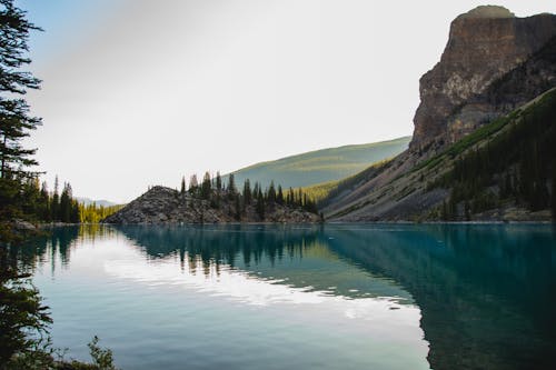 Free 白い空の下で湖の横にある緑と茶色の山 Stock Photo