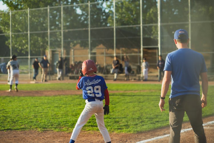 Unrecognizable Trainer With Sportsmen In Baseball Field