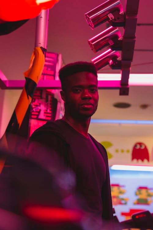 Free Young masculine black male in casual apparel with Afro haircut looking at camera in neon light Stock Photo