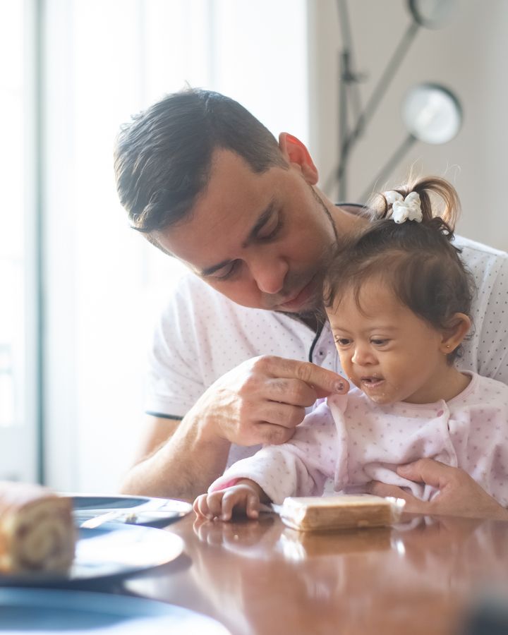 Father and daughter with Down syndrome having breakfast together at home