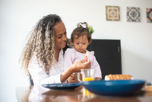 Free A loving mother feeds her young daughter breakfast at home, emphasizing care and togetherness. Stock Photo
