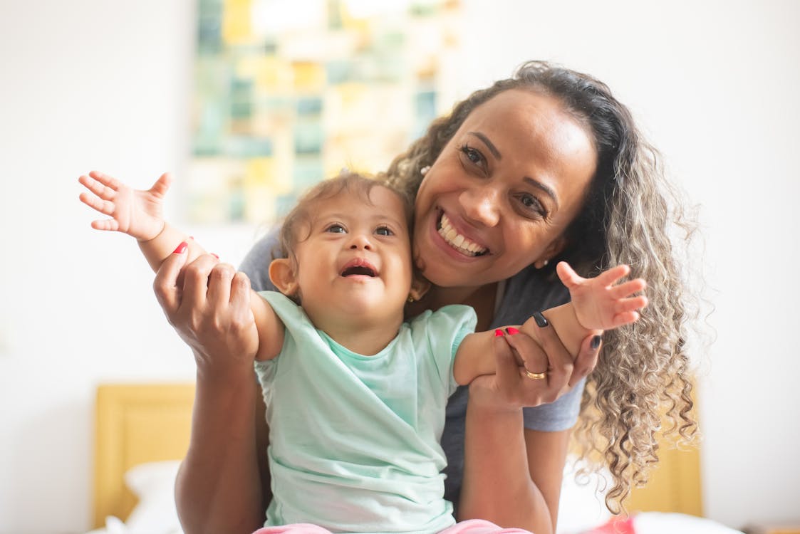 Free Photo of a Parent with Curly Hair Playing with Her Baby Stock Photo