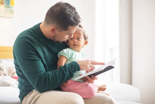 Photograph of a Father Reading a Book for Her Daughter