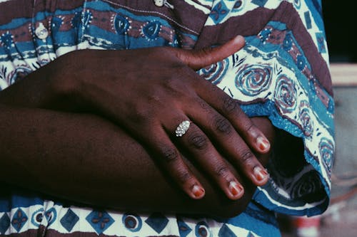 Crop anonymous African American female with stylish ring on finger in trendy shirt standing with crossed arms in daytime