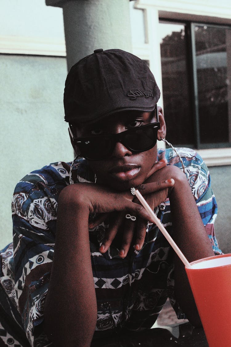 Pensive Black Person Sitting At Table With Cup Of Beverage