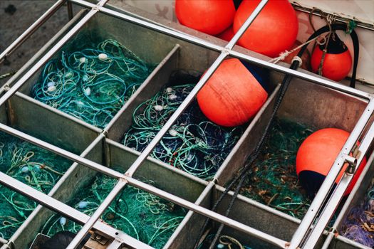 Close-up of fishing nets and buoys in metal compartments, symbolizing maritime industry.