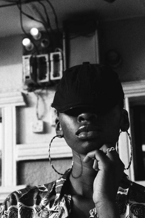 Black female in earring against wall of house
