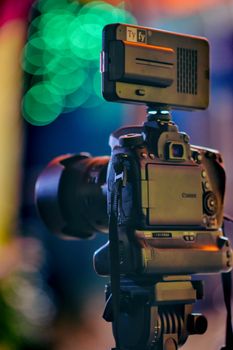 Close-up of a DSLR camera on a tripod with beautiful bokeh background.