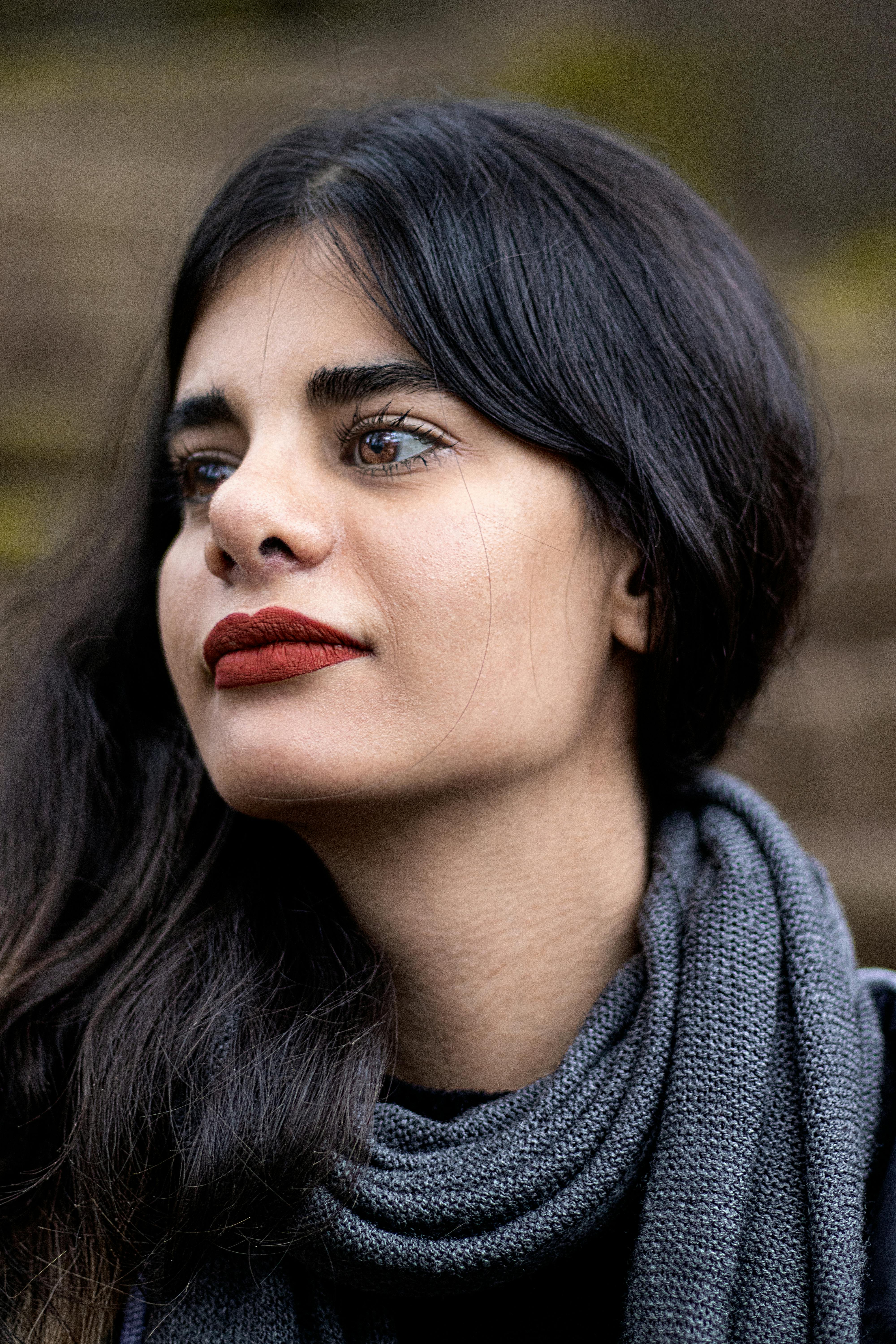 Close-up portrait of a woman with a gray scarf in an outdoor setting, showcasing natural beauty and elegance.