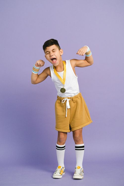 Free Young boy in sporty attire celebrating a victory with a medal and joyful expression. Stock Photo