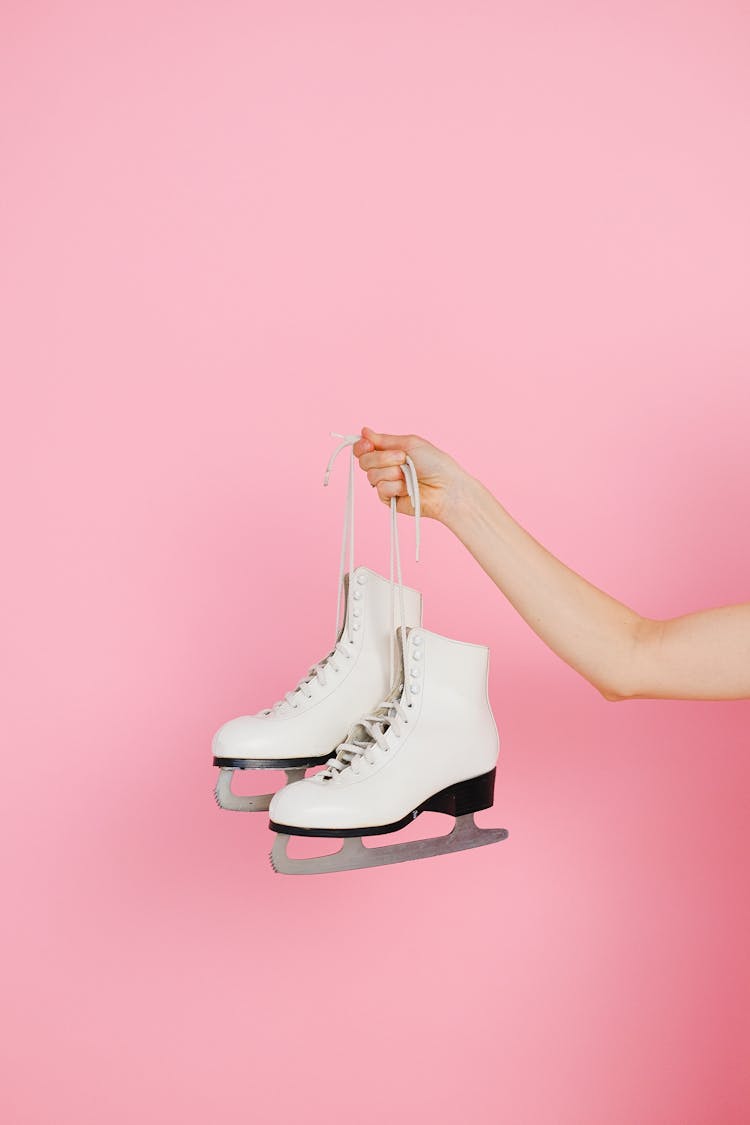 A Person Holding A Pair Of Ice Skating Shoes