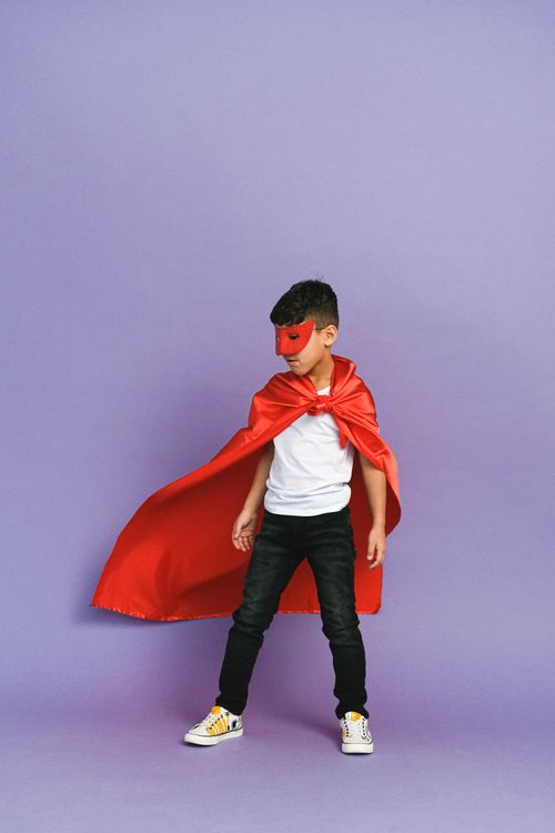 Free Young boy posing in superhero outfit, vibrant and playful studio portrait. Stock Photo